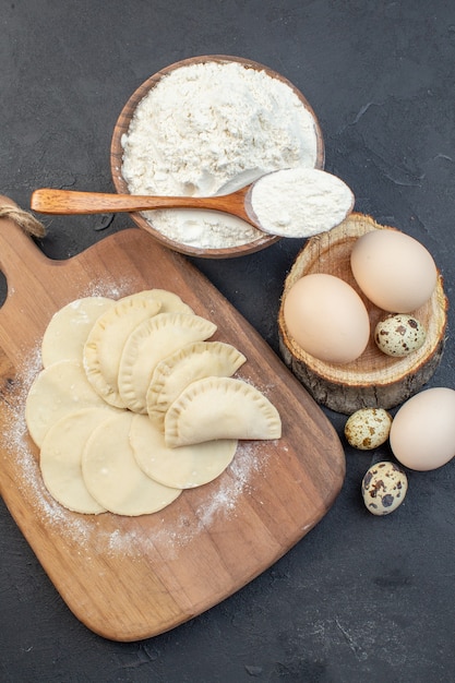 top view raw little hotcakes with flour and eggs on dark background pie dough oven cake cooking dust oil biscuit