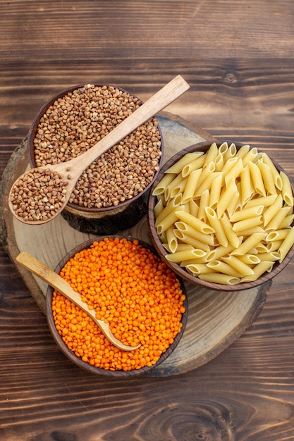 Top view raw little pasta with buckwheat and lentils on brown surface