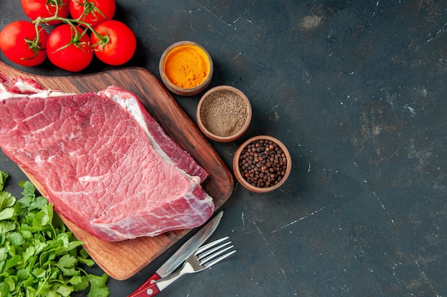 top view raw meat slice with red tomatoes and greens