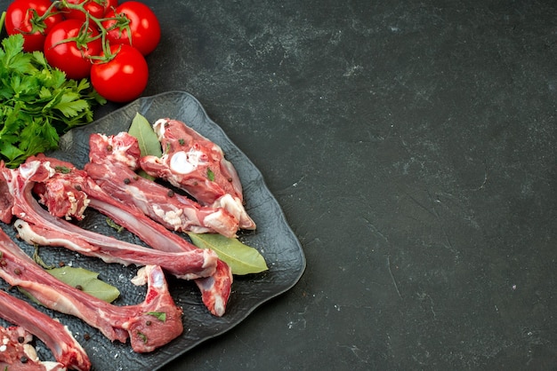 Top view raw meat slices with greens and red tomatoes on dark background dish meat butcher meal dinner salad food cooking