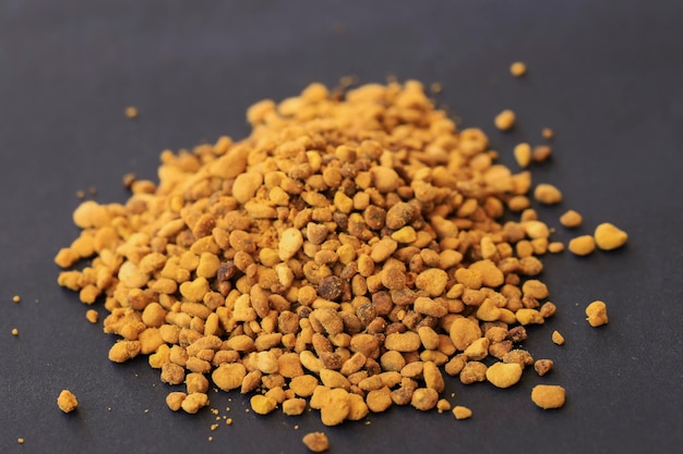 Top view on raw organic bee pollen granules on black background.