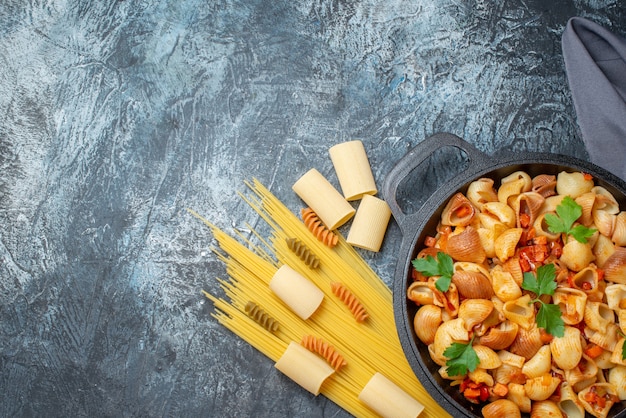 Photo top view raw pastas spaghetti rigatoni spirals tasty pasta in frying pan on grey background copy place