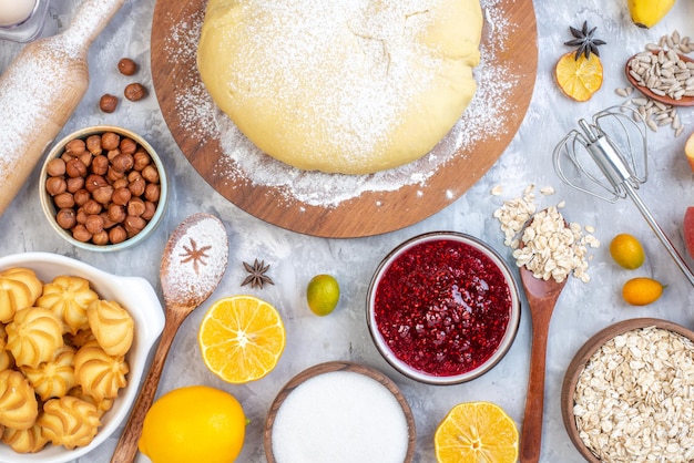 Top view of raw pastry flour on round board hazelnuts cookies lemon flour on stained white background