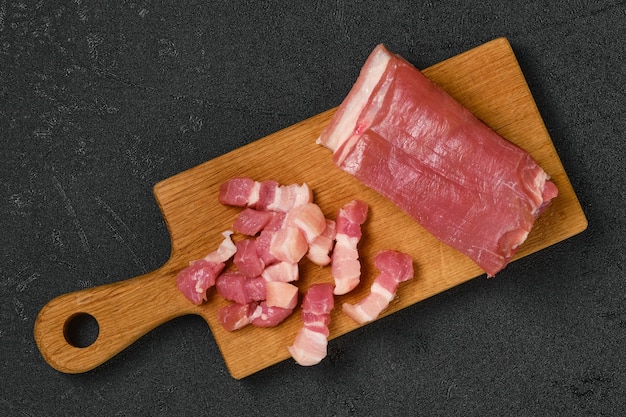 Vista dall'alto della pancetta di maiale cruda sul tagliere di legno