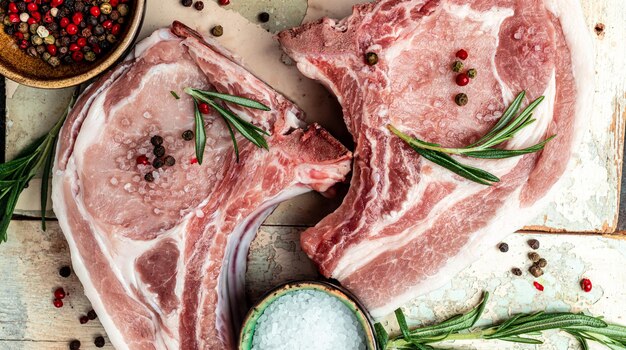 Top view raw pork chop steak with rosemary and salt pepper on wooden board Long banner format top view