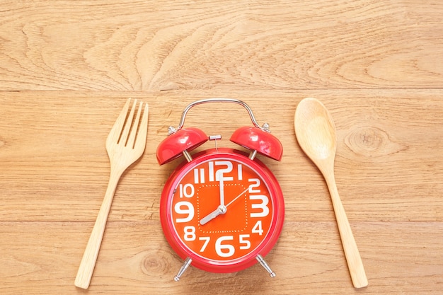 사진 나무 판자 배경에 나무 접시, 숟가락 및 포크에 상위 뷰 빨간색 알람 시계