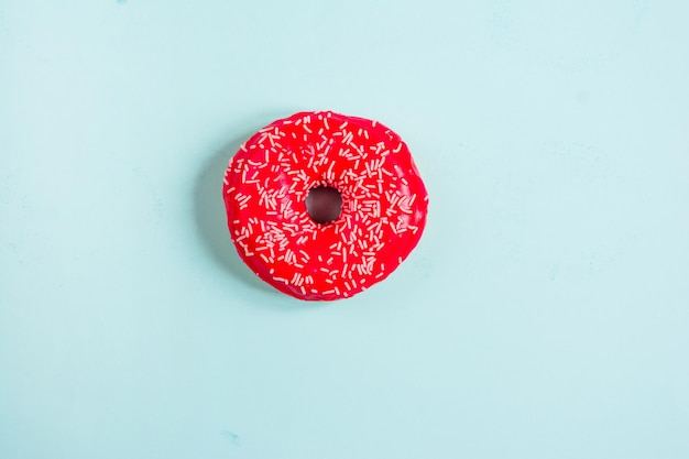 Top view of red glazed donut on blue background