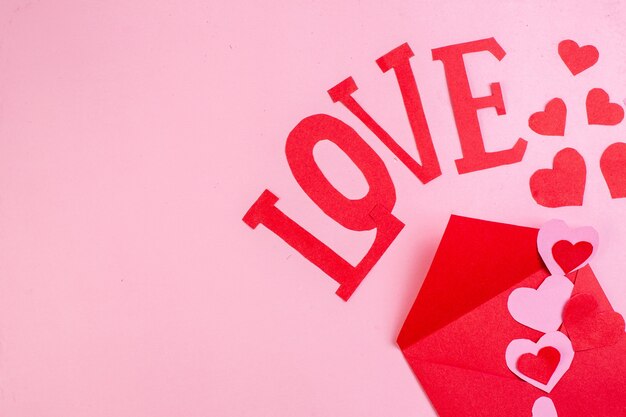 Photo top view red heart stickers love in capital letters red envelope on pink background copy place