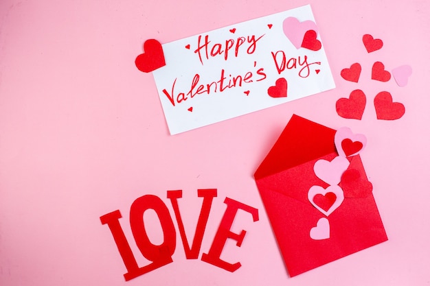 写真 上面図赤いハートのステッカーは大文字で大好きピンクの背景に紙に書かれた赤い封筒幸せなバレンタインデー