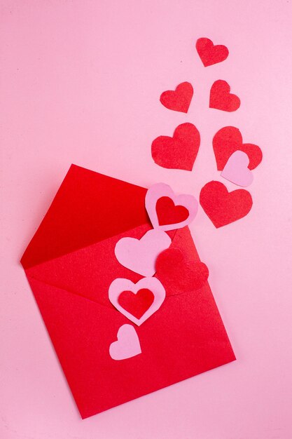 top view red heart stickers and red envelope on pink background