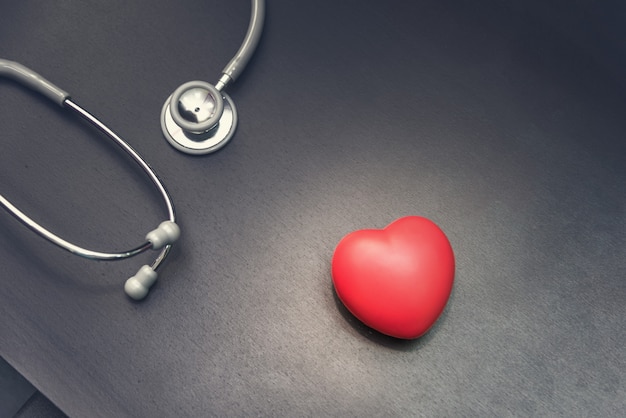 in top view, Red heart with stethoscope medical equipment on the doctor desk background