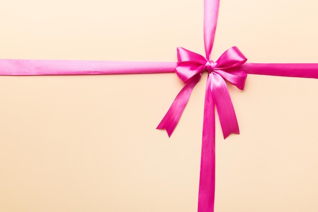 Top view of red ribbon rolled and red bow isolated on colored background flat lay with copy space