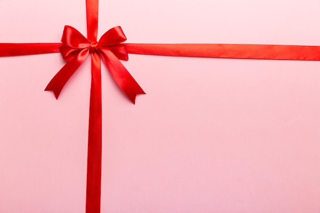 Top view of Red ribbon rolled and red bow isolated on colored background Flat lay with copy space