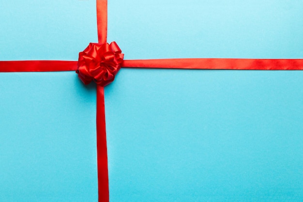 Top view of Red ribbon rolled and red bow isolated on colored background Flat lay with copy space