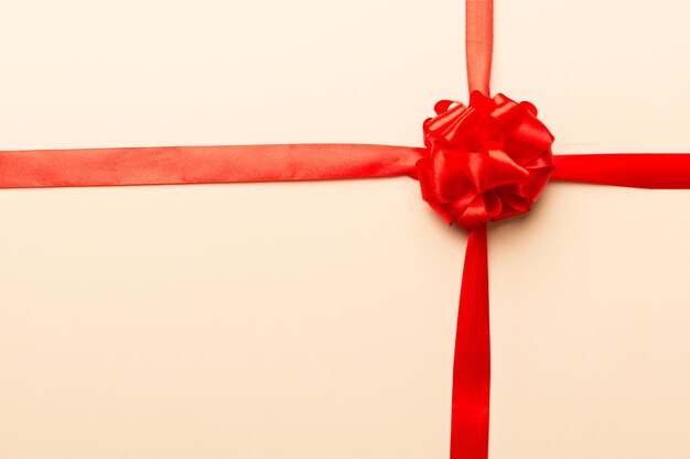 Top view of Red ribbon rolled and red bow isolated on colored background Flat lay with copy space