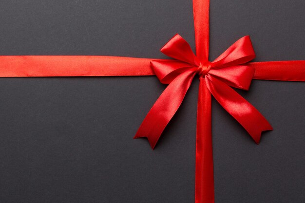 Top view of Red ribbon rolled and red bow isolated on colored background Flat lay with copy space