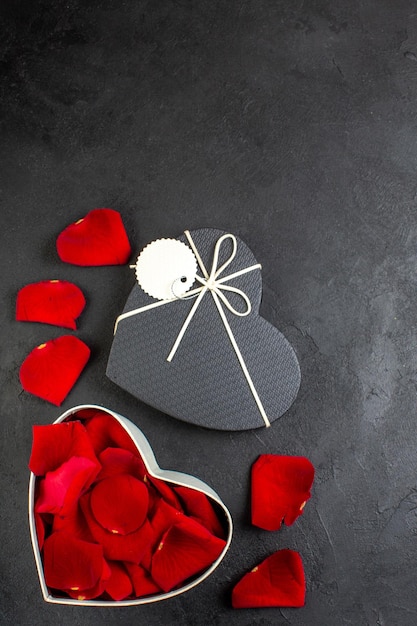 Vista dall'alto petali di rose rosse con rose rosse all'interno della scatola per san valentino su sfondo scuro cuore donna sentimento passione amore colore coppia