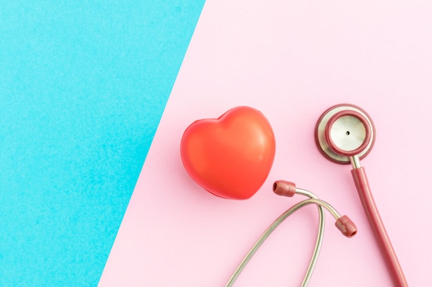 Top view red stethoscope and red heart shape on pink and blue