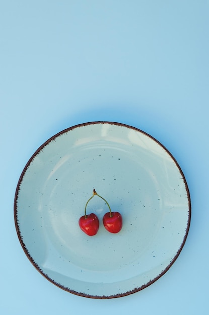 Top view of red sweet cherry on blue plate close up. Vegan, summer food concept. Diet