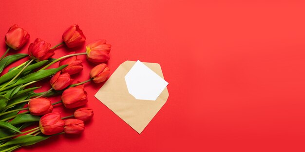 Top view of red tulips and craft envelope with a letter