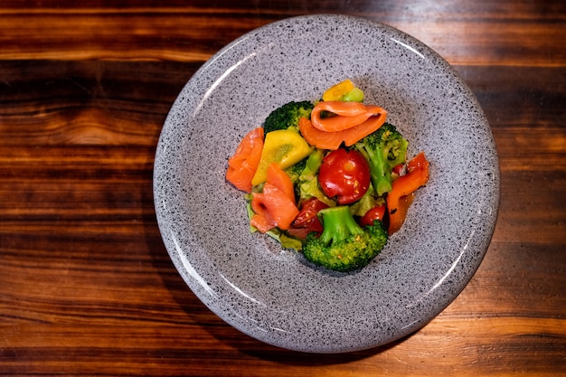 Vista dall'alto di rinfrescante insalata con salmone sulla bella lastra grigia sul bancone in legno