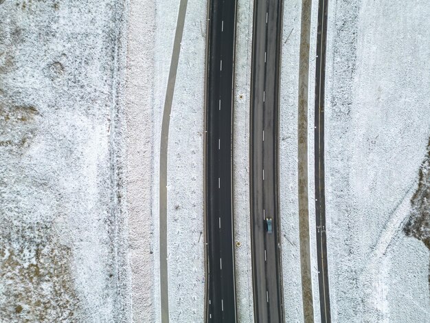 Photo top view of the roadway in winter snowcovered road and roadside the highway passes through the forest and the private sector detailed photos from the drone of the road infrastructure