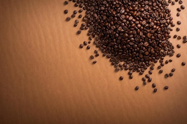 Top view of roasted coffee beans scattered on brown paper texture background with copy space
