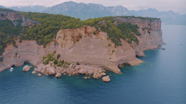 Top view of a rocky shore covered with green trees Cave in the rock Blue clear water Seascape