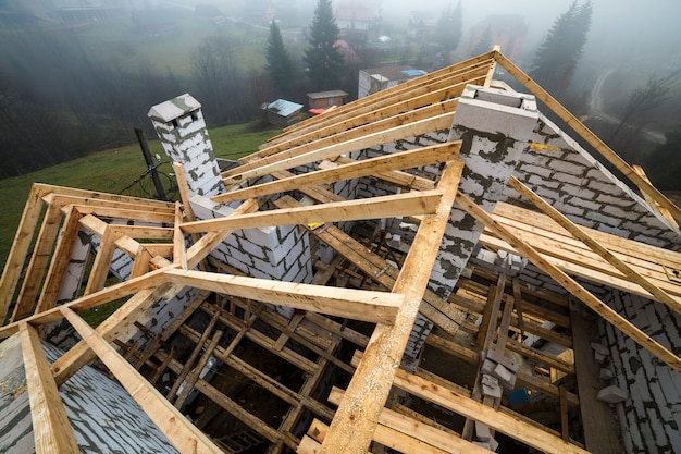 Top view of roof frame from wooden lumber beams and planks on walls made of hollow foam insulation blocks.