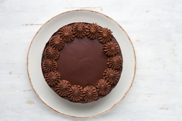 Top view of round baked chocolate cake on a light wooden surface. 