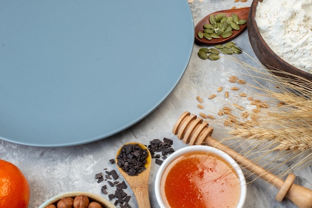 Top view round plate flour and honey bowl honey stick on table