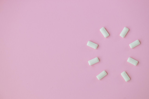 Top view of round shape from white chewing gums on pink\
background