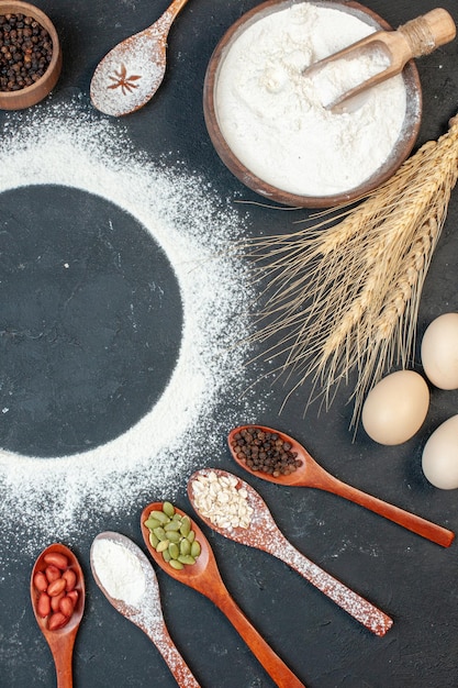 Top view round shaped flour with eggs seeds and seasonings on dark background cookie cake fruit white color tea biscuit sugar