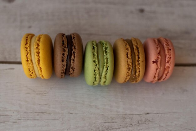 Top view of row of colorful macaroons on aged white wood background close up