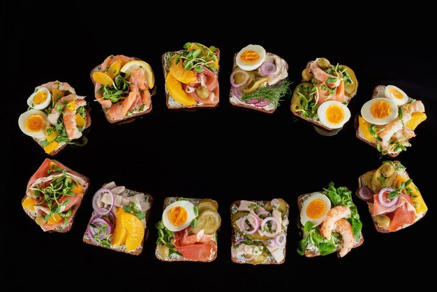 Top view of rye bread with prepared danish smorrebrod sandwiches isolated on black