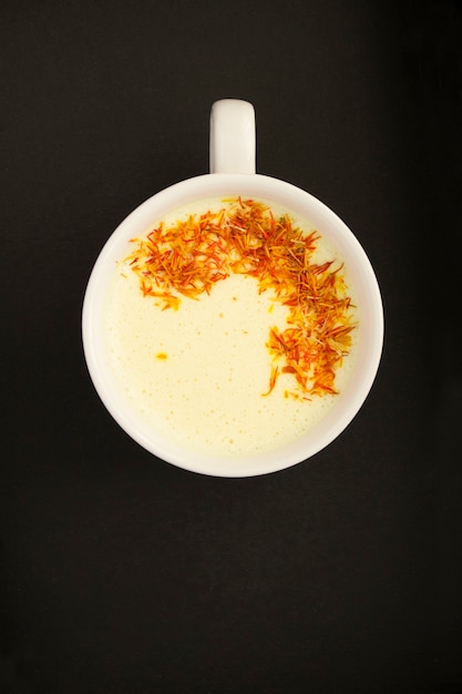 Top view of saffron latte or saffron moon milk in the white cup on black