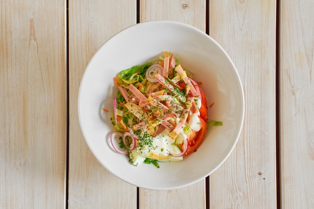 Top view of salad with ham, tomato, red onion and egg