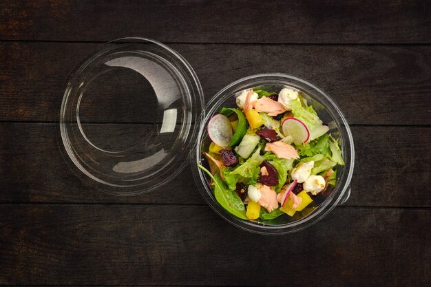 Top view of salad with salmon, radish, zucchini and beetroot in take away package