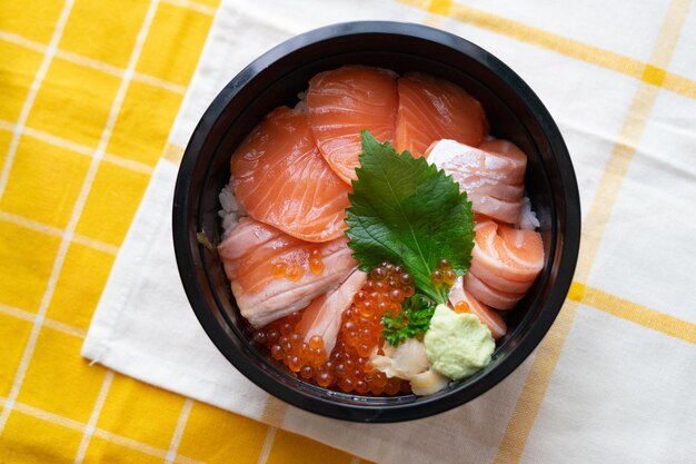 Top view of salmon don fresh sashimi raw salmon salmon roe wasabi pickled ginger on sour rice