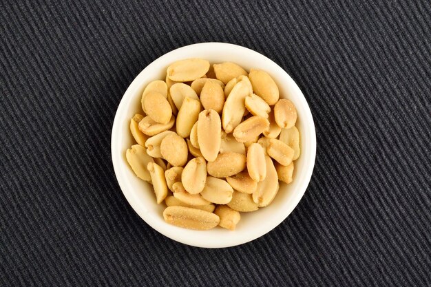 Top View of Salted Peanuts in Bowl on Blue Textured Cloth