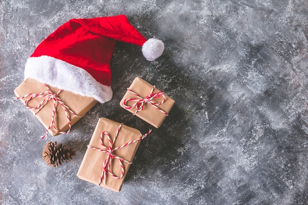 Top view of santa hat with gift packages wrapped in brown paper 