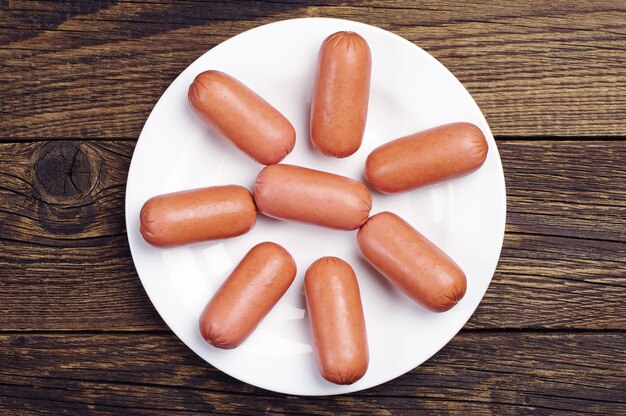 Top view on sausages on a plate on wooden table