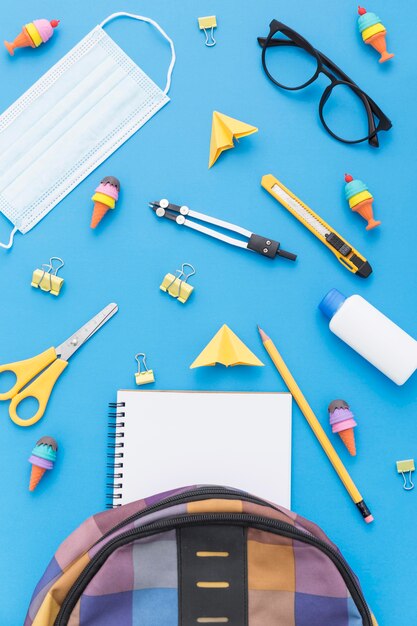 Top view of school supplies with book bag and glasses