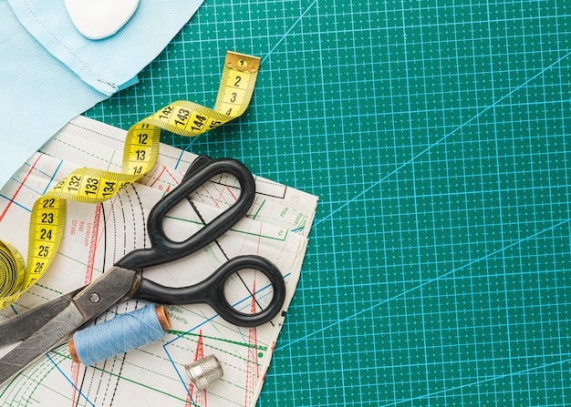 Photo top view of scissors with measuring tape and thread