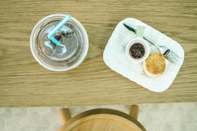 Top view scones with jam and ice coffee on the table.