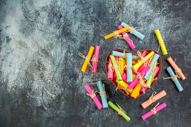 top view scroll colored wish papers in heart shaped box on dark background with free space