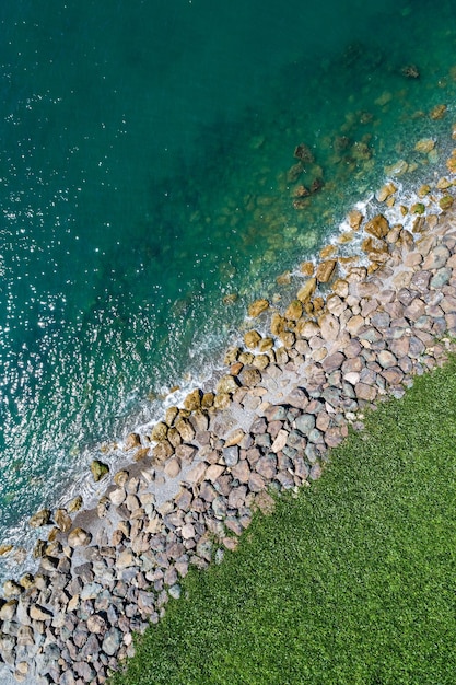 Top view of the sea coast. Green grass, stones and turquoise water