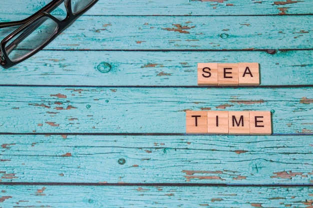 Top view sea time lettering of alphabet wooden blocks on blue wooden background