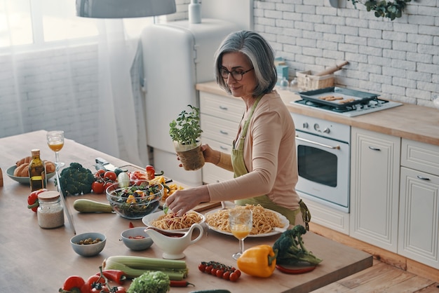 家で時間を過ごしながら健康的な夕食を調理するエプロンで年配の女性の上面図