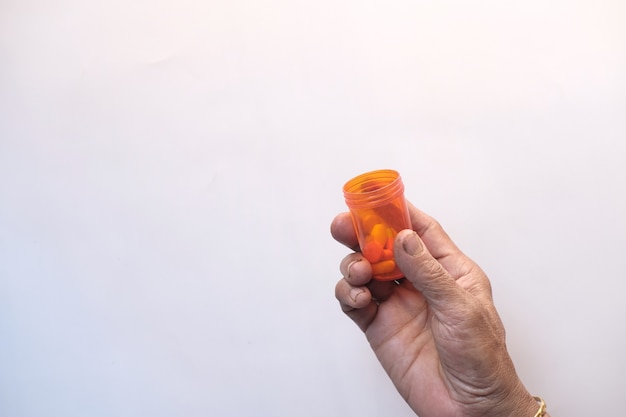 Top view of senior women holding pill container on white background .